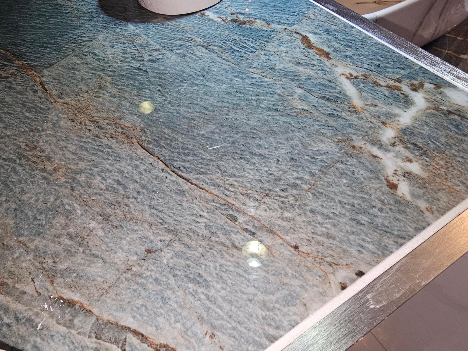 Close-up of a polished blue-green veined vanity top with a brushed-metal edge trim.